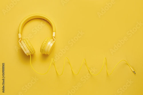 Photo of stylish yellow headphone on yellow background. Music concept.