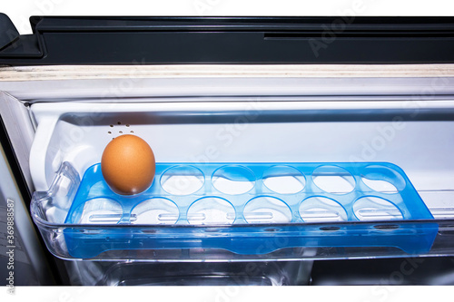 The last egg in refrigerator isolated on white background. Single chicken egg on plastic tray in refrigerator door isolated