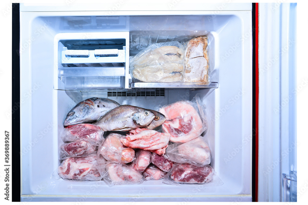 Many meat in refrigetator freezer isolated on white background. Closeup lot of raw pork, fish, meat and chicken in freezing compartment