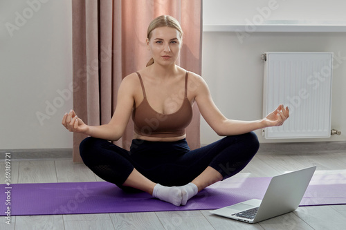 A beautiful slender girl goes in for sports in a sports top. Next to the laptop.