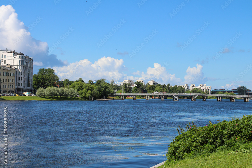 City landscape - river, houses, bridge against the background of a blue sky with clouds. St. Petersburg