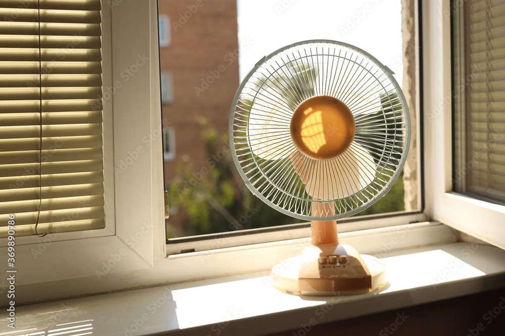Obraz Hot. Ventilator fan is on the windowsill, the window is open fototapeta, plakat