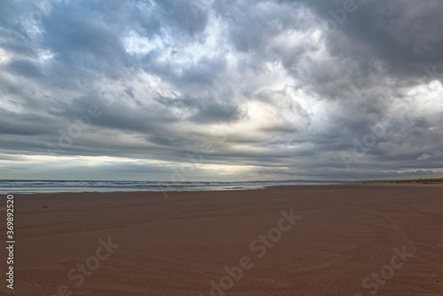 The wide stretch of deserted sand at St Cyrus Beach at low Tide under the dramatic skies of a Summer Storm in September.