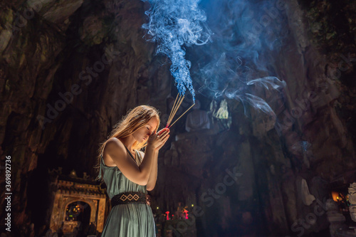 Fotografía Young woman praying in a Buddhist temple holding incense Huyen Khong Cave with s