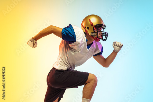 Leader. American football player isolated on gradient studio background in neon light. Professional sportsman during game playing in action and motion. Concept of sport, movement, achievements.