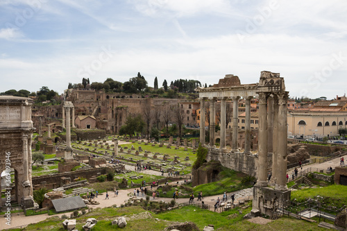 Top view of the Roman forum, illuminated by the sun, against a blue sky. Ancient architecture and urban landscape of historical Rome.