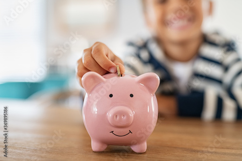 Foto Smiling child saving money in piggybank