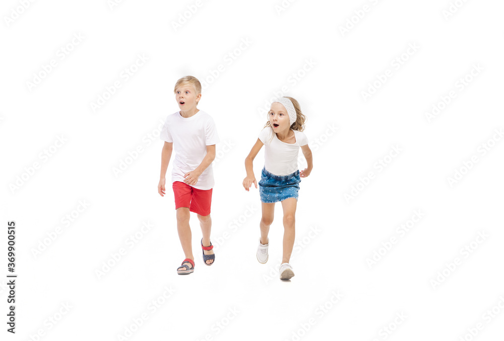 Energy. Happy kids, little emotional caucasian boy and girl jumping and running isolated on white background. Look happy, cheerful, sincere. Copyspace for ad. Childhood, education, happiness concept.