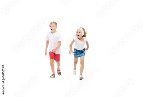 Energy. Happy kids, little emotional caucasian boy and girl jumping and running isolated on white background. Look happy, cheerful, sincere. Copyspace for ad. Childhood, education, happiness concept.