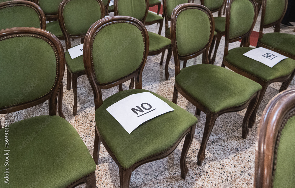 Alternately assigned seats in a conference or ceremony during the coronavirus pandemic due to social distancing provisions. Paper sheets saying no on top. - obrazy, fototapety, plakaty 