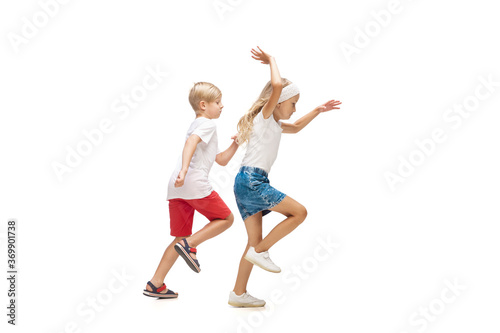 Step by step. Happy kids, little emotional caucasian boy and girl jumping and running isolated on white background. Look happy, cheerful, sincere. Copyspace for ad. Childhood, education, happiness