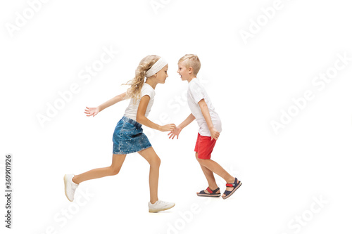 Friendship. Happy kids, little emotional caucasian boy and girl jumping and running isolated on white background. Look happy, cheerful, sincere. Copyspace for ad. Childhood, education, happiness