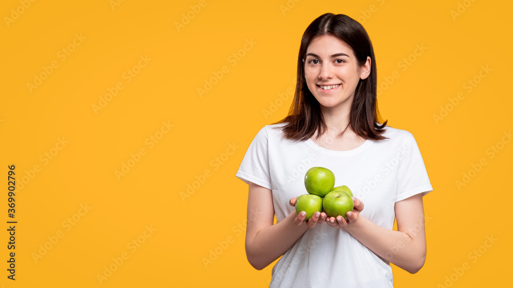Healthy diet. Vegetarian lifestyle. Cheerful woman in white casual t-shirt holding fresh green apples pile isolated on orange copy space. Organic fruit. Healthy diet. Antioxidant food. Healthy diet. Vegetarian lifestyle. Cheerful woman in white casual t-shirt holding fresh green apples pile isolated on orange copy space. Organic fruit. Healthy diet. Antioxidant food.