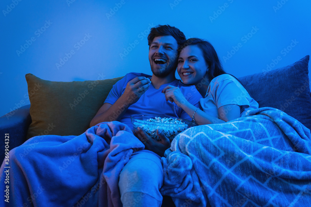 Young and happy couple watching comedy TV show