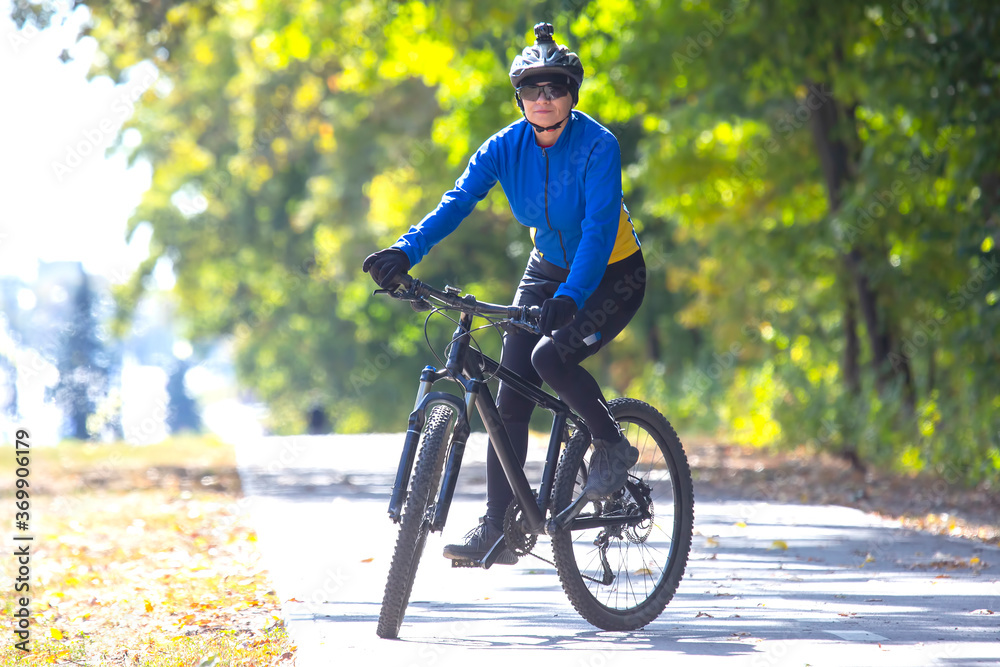 Obraz premium Beautiful girl cyclist rides a bicycle. Healthy lifestyle and sport. Leisure and hobbies