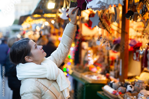 Attractive woman choosing wooden decoration on outdoor Christmas market. High quality photo
