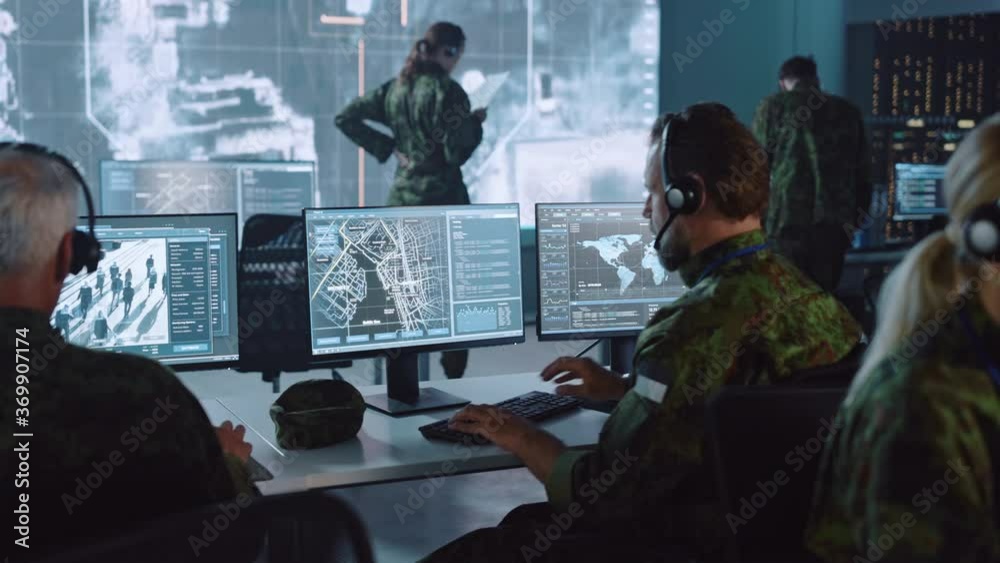 Military Surveillance Officer Working on a City Tracking Operation in a Central Office Hub for Cyber Control and Monitoring for Managing National Security, Technology and Army Communications.