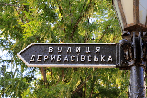 Vintage road sign stands on Deribasovskaya Street in the famous city Odessa, Ukraine. Deribasivska street is popular from Ukrainian and foreign tourists photo