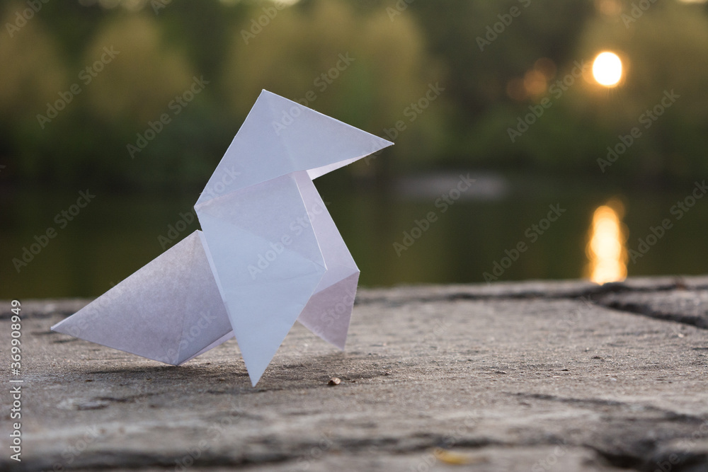 A paper crane standing before the water