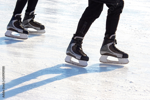 Legs of a man skating on an ice rink. Hobbies and sports. Vacations and winter activities