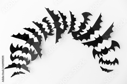 halloween  decoration and scary concept - flock of black paper bats flying over white background