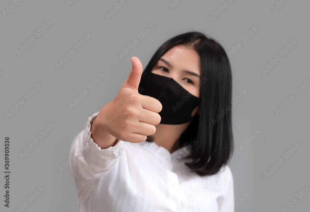 Asian women show thumb up and wearing mask trying to protect from coronavirus epidemic. Asian women show thumb up and wearing mask trying to protect from coronavirus epidemic.