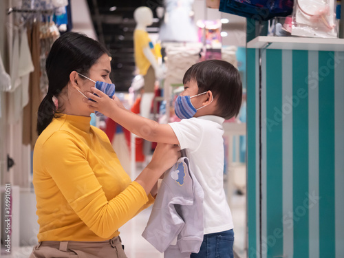 Mother and son are shopping at toy store and wear protective mask on their face from virus infected air outbreak.