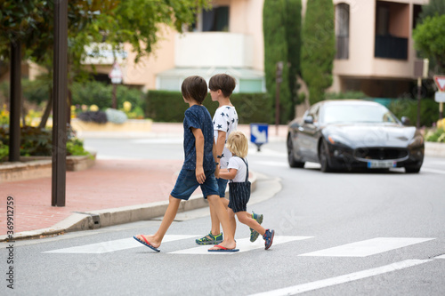 Children, boy brothers, siblings holding hands and crossing crosswalk on the street
