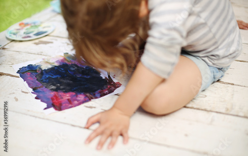 Preschooler kid learns art. Little girl draws a colorful painting outside with watercolor paint on summer day. Creativity in childhood. Kindergarten activities for toddlers. 