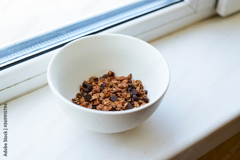 Healthy chocolate chip granola in the white bowl, breakfast time Healthy chocolate chip granola in the white bowl, breakfast time