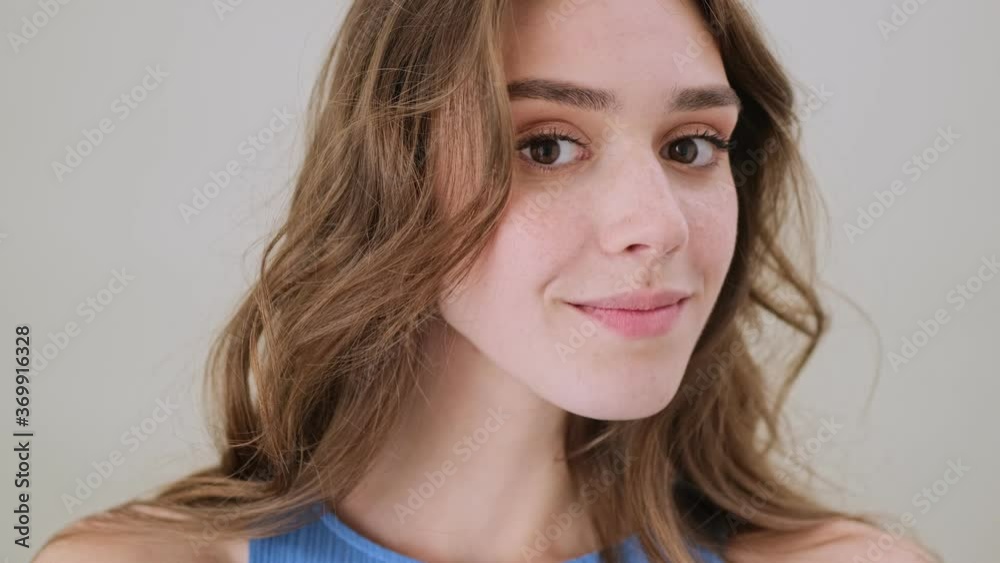A beautiful young woman is looking to the camera standing isolated over gray background in studio A beautiful young woman is looking to the camera standing isolated over gray background in studio