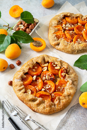 Healthy pastries made from rye flour, dessert diet food. Galette with apricots and nuts on a light stone table. photo