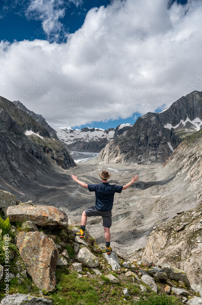 hiker with outstreched arms over Oberaletsch Glacier in the Swiss Alps
