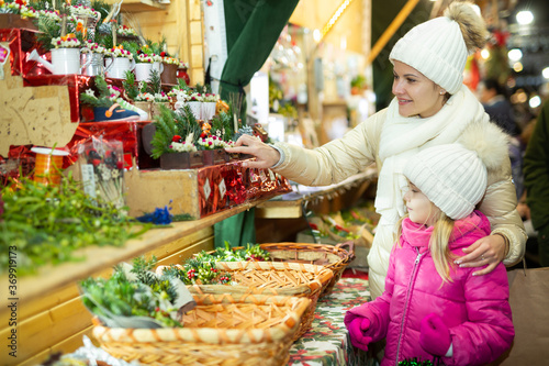 Joyous mother with little daughter buying decorations for Xmas at an open air market. High quality photo