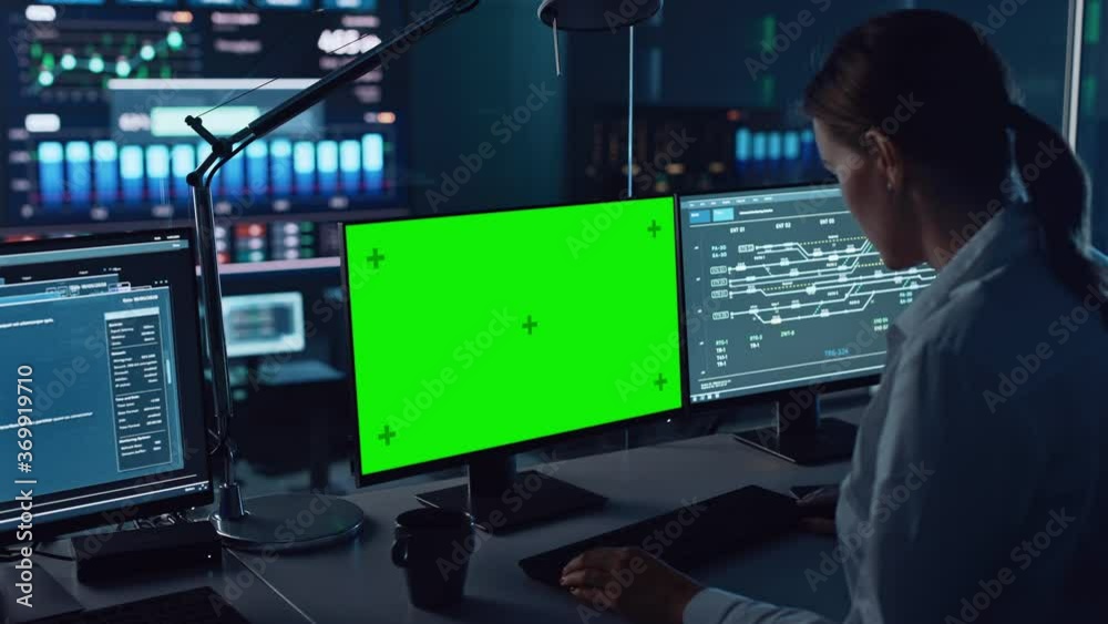 Female Software Engineer Working in a Modern Monitoring Office with Green Screen Mock Up on a Computer Display. Monitoring Room Big Data Scientists and Managers Sit in Front of Computers.