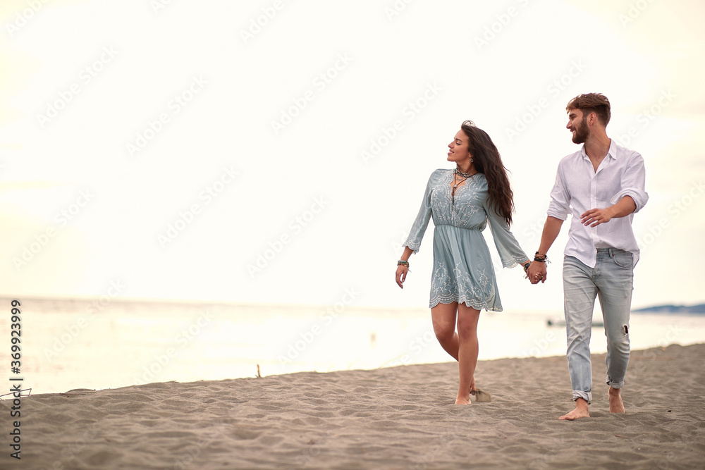 beautiful young couple walking barefoot on sandy beach holding hands beautiful young couple walking barefoot on sandy beach holding hands
