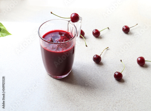 Wallpaper Mural A glass of cherry juice in a glass mug on the kitchen table with scattered cherries, side view Torontodigital.ca