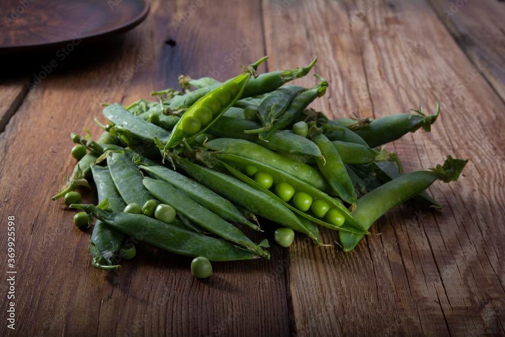 a branch of green peas with pods on a wooden table close-up, harvest from the garden a branch of green peas with pods on a wooden table close-up, harvest from the garden