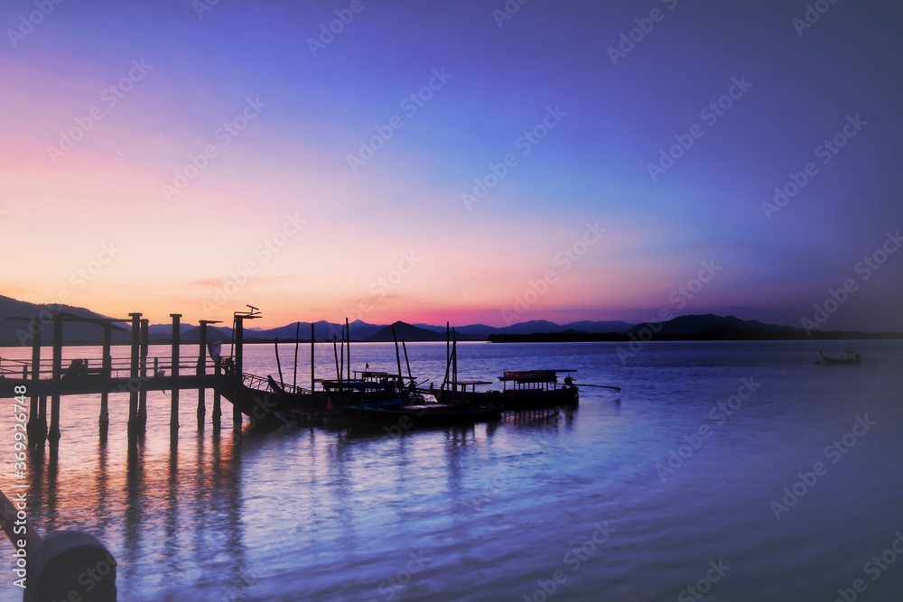 Silhouette fishing boats parking in harbour. Beautiful morning sunrise at Koh Phra Thong island, Phang Nga, Thailand.
