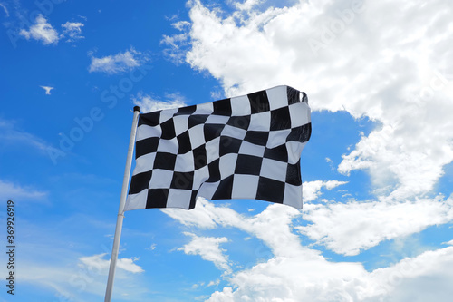 Checkered flag old condition on flagpole waving in the wind with clouds on background , by adjusting the focus the flagpole of the image The concept of flags are waving and moving.