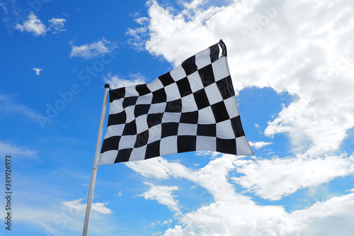 Checkered flag old condition on flagpole waving in the wind with clouds on background , by adjusting the focus the flagpole of the image The concept of flags are waving and moving. © wutthiphat