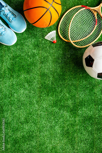Sport balls and badminton rackets on football grass. Top view copy space