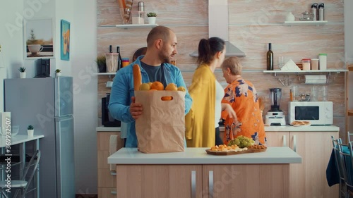 Man returning from market with fruits and bread. Young couple coming from shopping bringing a paper bag with groceries, fresh food, from supermarket at parents home to prepare a family dinner photo