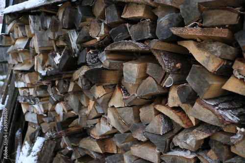 Pile of firewood background. Winter countryside village stack of wood. Logs for fire. Natural forest material timber.
