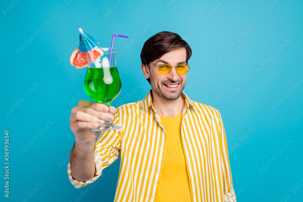 Toast great holidays. Positive guy enjoy travel exotic sea beach resort raise glass green cocktail wear white yellow clothes isolated over blue color background