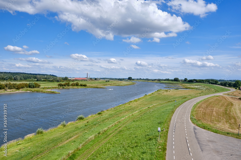 Typical Dutch river landscape with cows, grassland, floodplain, dike with road and the river Rhine with groyne in river bend near Wageningen, Gelderland, the Netherlands Typical Dutch river landscape with cows, grassland, floodplain, dike with road and the river Rhine with groyne in river bend near Wageningen, Gelderland, the Netherlands