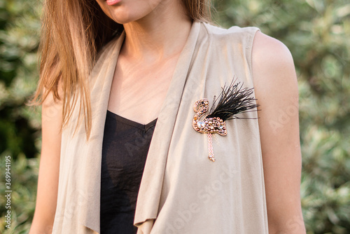 Woman wearing a handmade flamingo brooch made of beads and stones