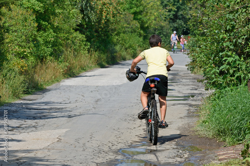 On a summer day a boy rides a Bicycle along a Park path