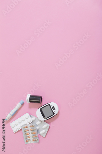 glucometer and pills on pink background
