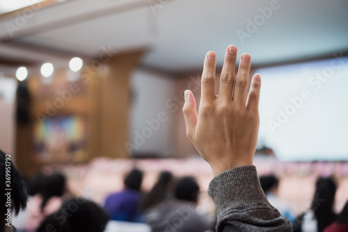 Audience or students raising hands up at conference to answer question while speaker speech at seminar hall with crowd groups, arms of large group in classroom for vote or questions